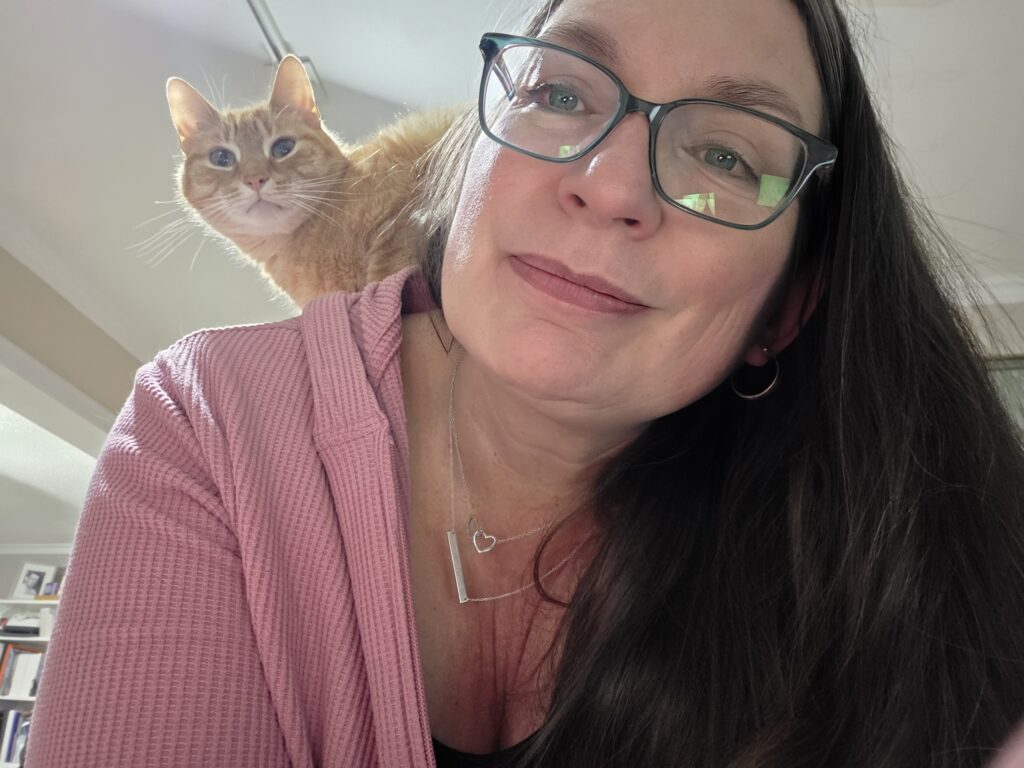 Photo of Kim with a cat on her shoulder
